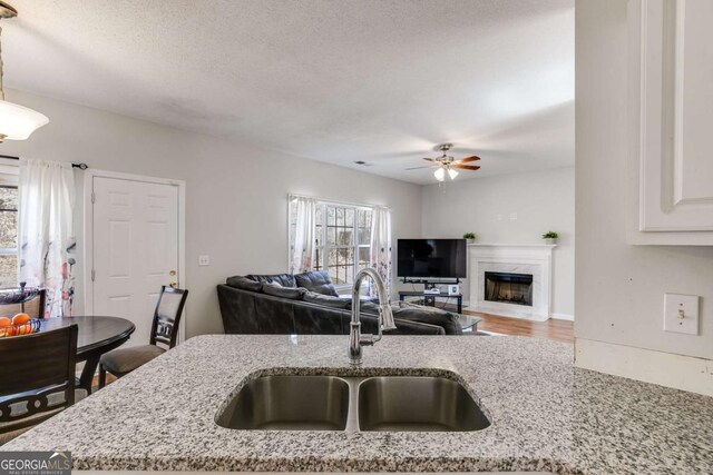 kitchen with light stone counters, open floor plan, and a sink