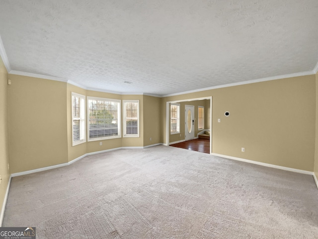 carpeted spare room with crown molding, a textured ceiling, and baseboards