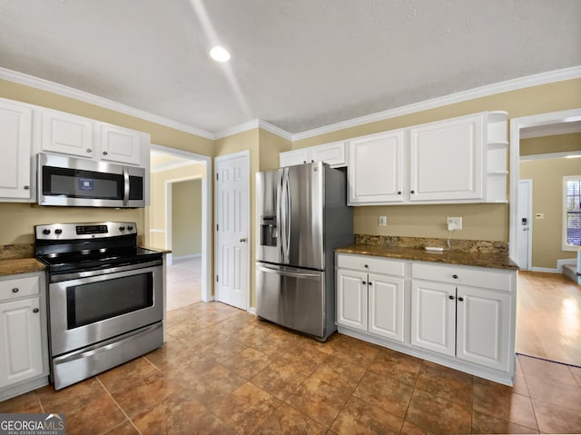 kitchen with ornamental molding, appliances with stainless steel finishes, white cabinetry, and baseboards