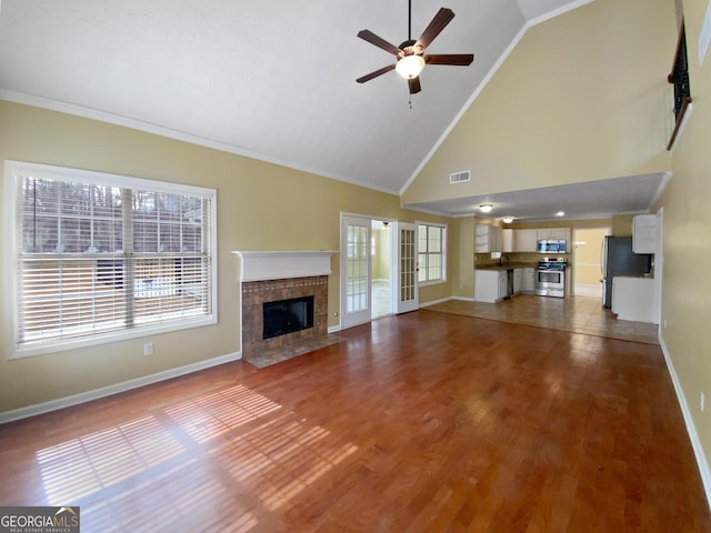 unfurnished living room with baseboards, visible vents, wood finished floors, crown molding, and a high end fireplace