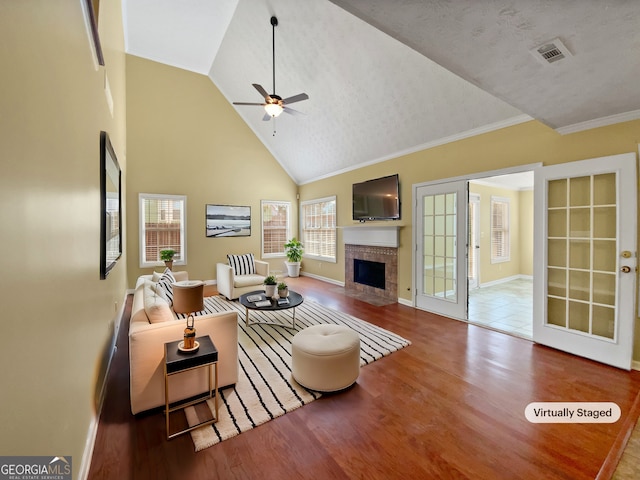 living room with visible vents, a ceiling fan, wood finished floors, a fireplace, and high vaulted ceiling