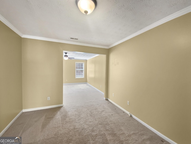 carpeted empty room with a textured ceiling, ornamental molding, visible vents, and baseboards