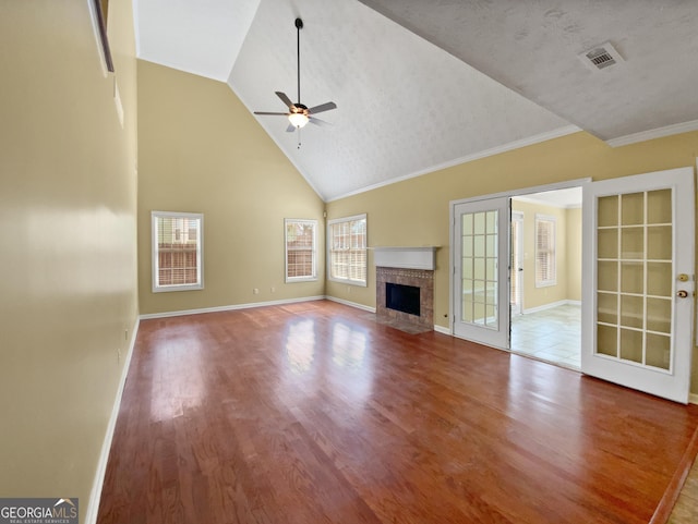 unfurnished living room featuring ceiling fan, a fireplace, wood finished floors, visible vents, and baseboards