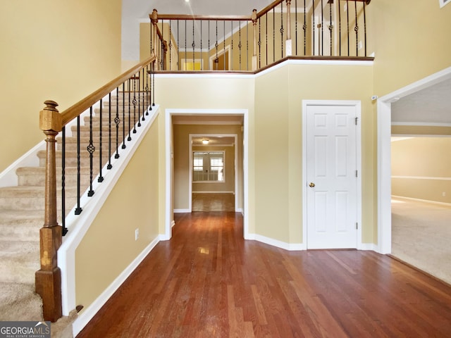 interior space with a towering ceiling, stairway, baseboards, and wood finished floors