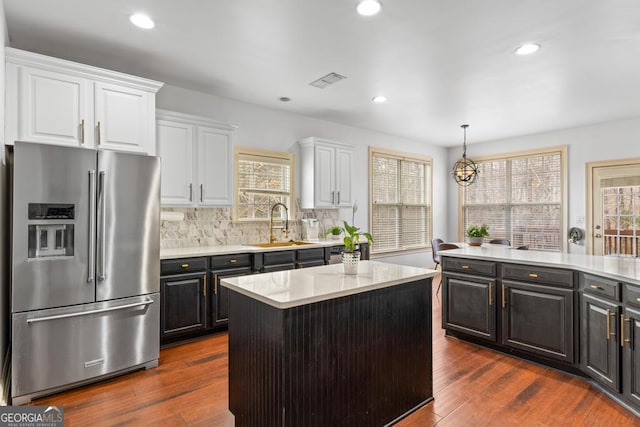 kitchen with a sink, visible vents, white cabinetry, stainless steel fridge with ice dispenser, and a center island