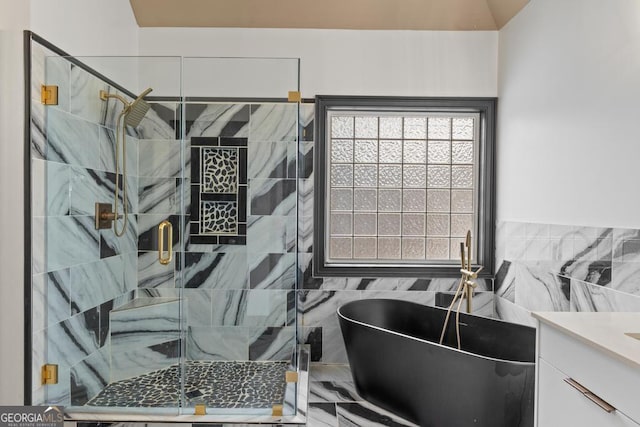 full bath featuring tile walls, a freestanding bath, vanity, and a shower stall