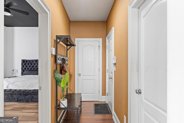 corridor with baseboards and dark wood-type flooring