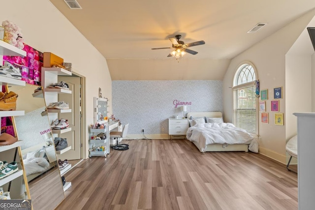 bedroom featuring visible vents, light wood-style flooring, vaulted ceiling, baseboards, and wallpapered walls