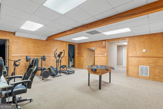 workout area featuring a paneled ceiling, wood walls, visible vents, and carpet flooring