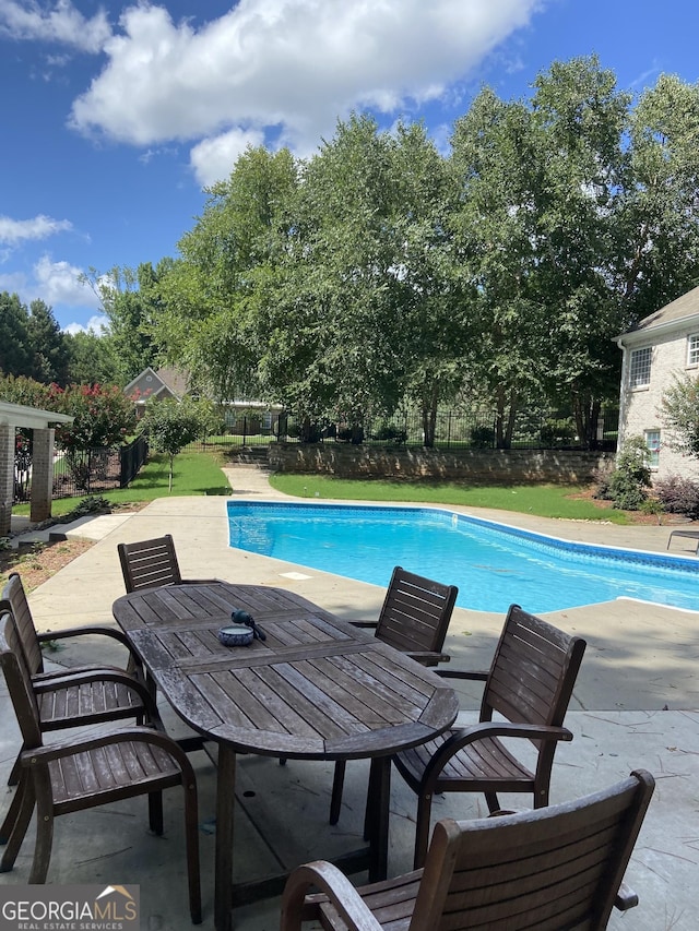 pool with outdoor dining area, a patio area, and fence