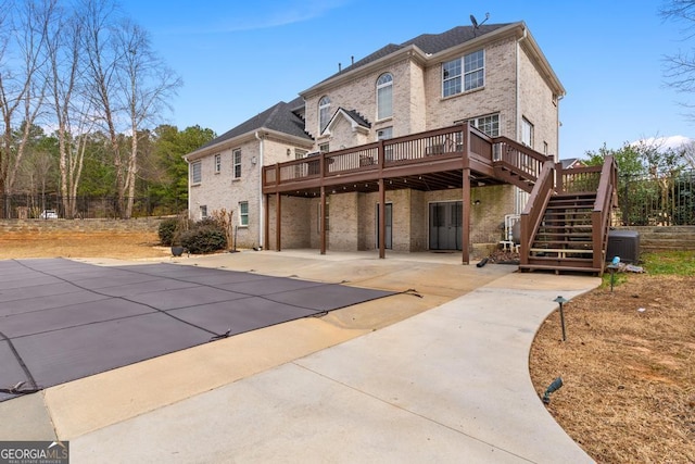 rear view of property featuring brick siding, stairway, a wooden deck, and central air condition unit