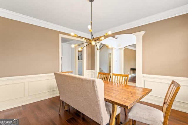 dining space featuring dark wood-style floors, a wainscoted wall, arched walkways, and ornate columns