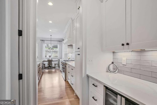 kitchen featuring high end stainless steel range oven, white cabinetry, light wood-style floors, and recessed lighting