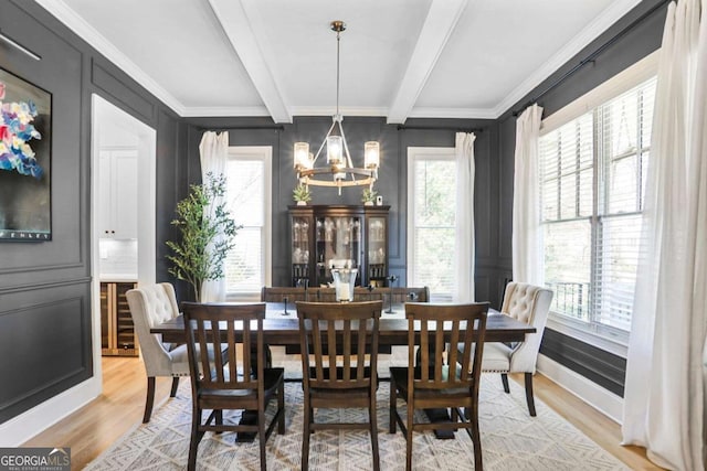 dining space with a chandelier, light wood-style floors, crown molding, and beamed ceiling