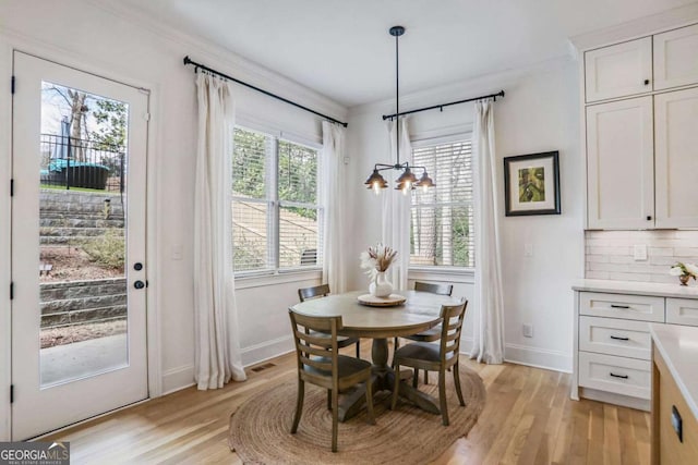 dining space featuring light wood finished floors, baseboards, ornamental molding, and an inviting chandelier