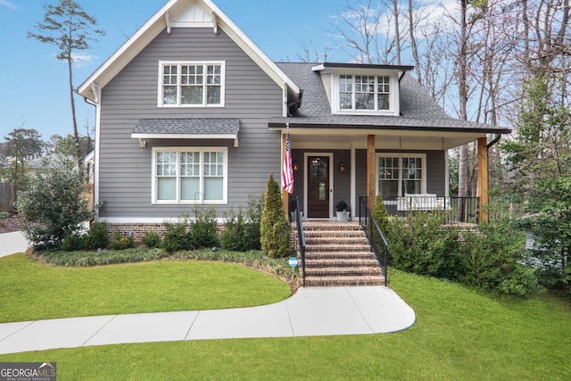 view of front of home with roof with shingles, a porch, and a front yard