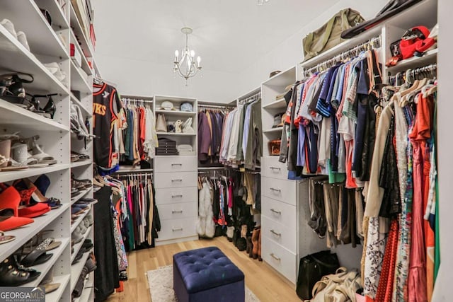 walk in closet featuring light wood finished floors and an inviting chandelier