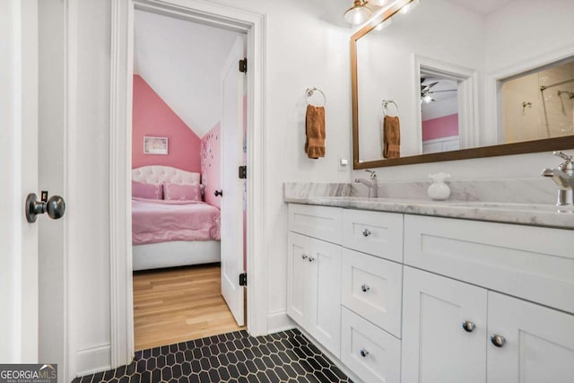 bathroom featuring wood finished floors, double vanity, a sink, and ensuite bathroom