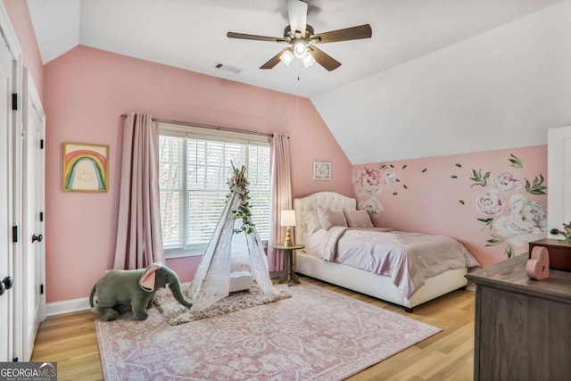 bedroom with a ceiling fan, baseboards, vaulted ceiling, visible vents, and light wood-style floors