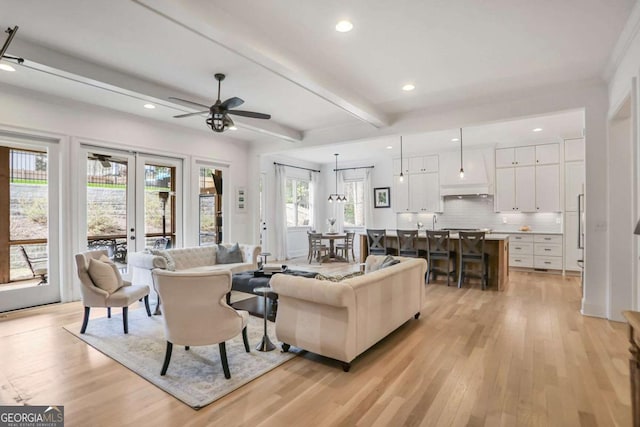 living area featuring recessed lighting, light wood-style flooring, beamed ceiling, and french doors