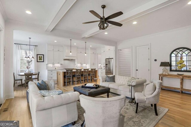 living room with visible vents, a ceiling fan, ornamental molding, beam ceiling, and light wood finished floors