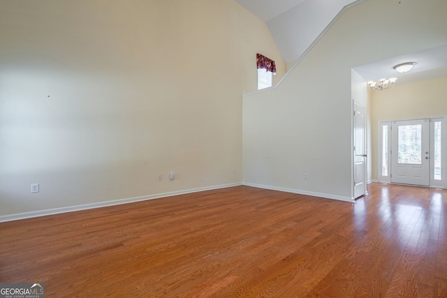 entryway with high vaulted ceiling, baseboards, an inviting chandelier, and wood finished floors