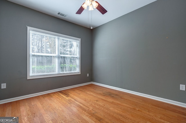 empty room with ceiling fan, wood finished floors, visible vents, and baseboards