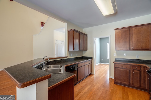 kitchen featuring black dishwasher, dark countertops, a peninsula, light wood-style floors, and a sink