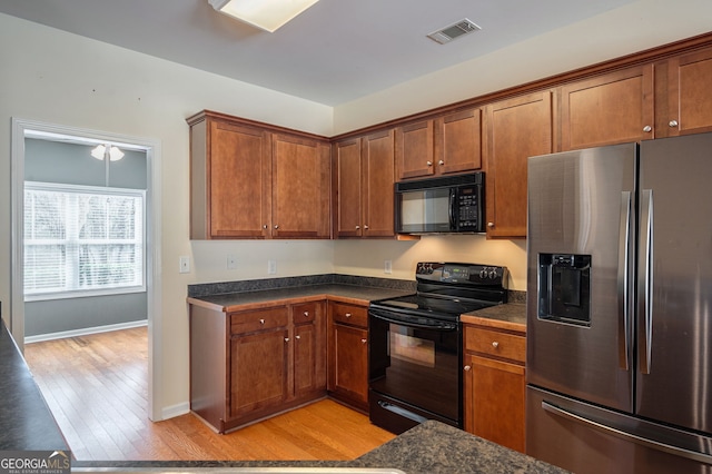 kitchen featuring black appliances, visible vents, brown cabinetry, and light wood-style floors