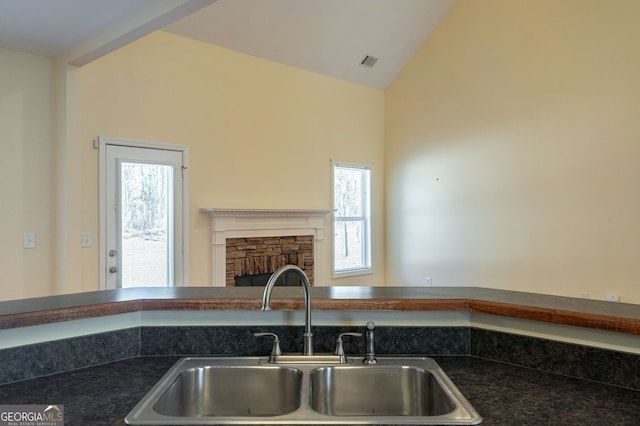 kitchen with dark countertops, a fireplace, a sink, and visible vents