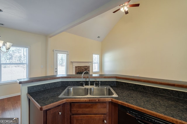 kitchen featuring black dishwasher, dark countertops, open floor plan, a fireplace, and a sink