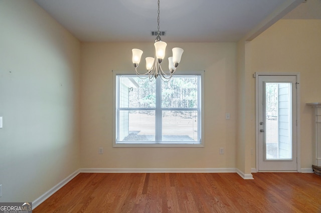 unfurnished dining area featuring light wood finished floors, baseboards, visible vents, and an inviting chandelier