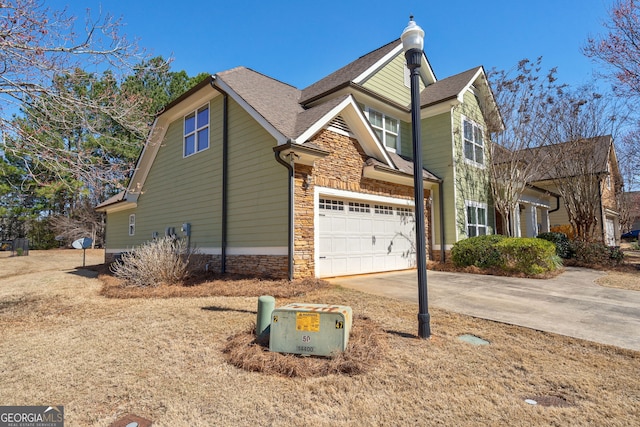 view of property exterior featuring driveway, stone siding, a garage, and roof with shingles