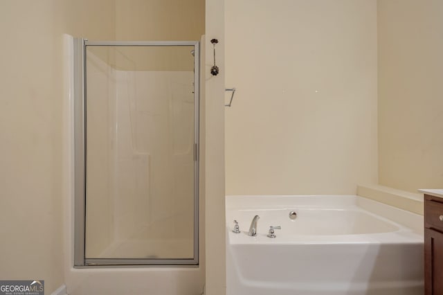 bathroom with a stall shower, a garden tub, and vanity