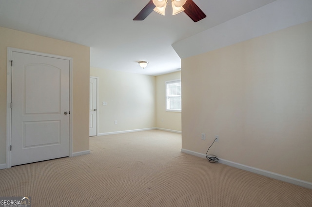 spare room featuring baseboards, ceiling fan, and light colored carpet