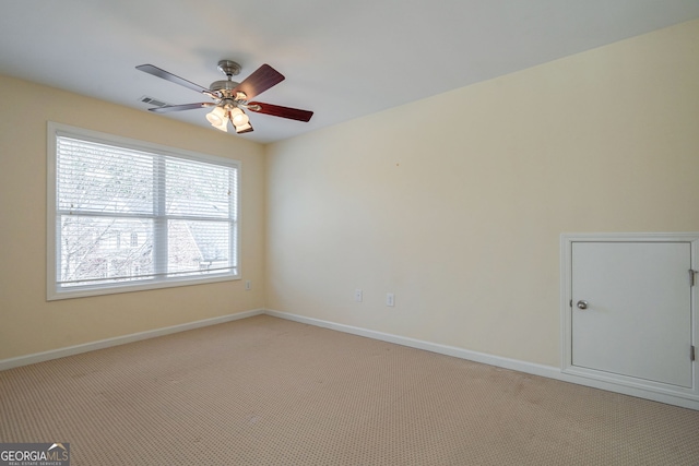 spare room with baseboards, ceiling fan, visible vents, and light colored carpet