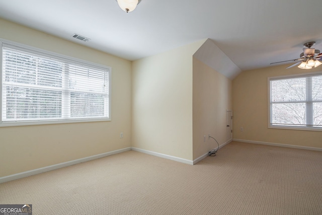 additional living space with light carpet, a ceiling fan, visible vents, and baseboards