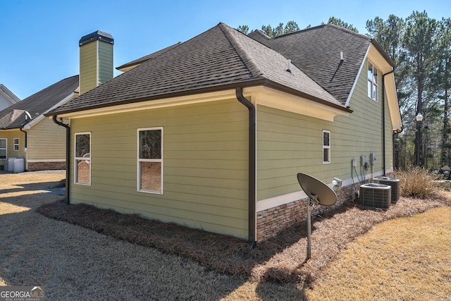 view of home's exterior with roof with shingles and a chimney