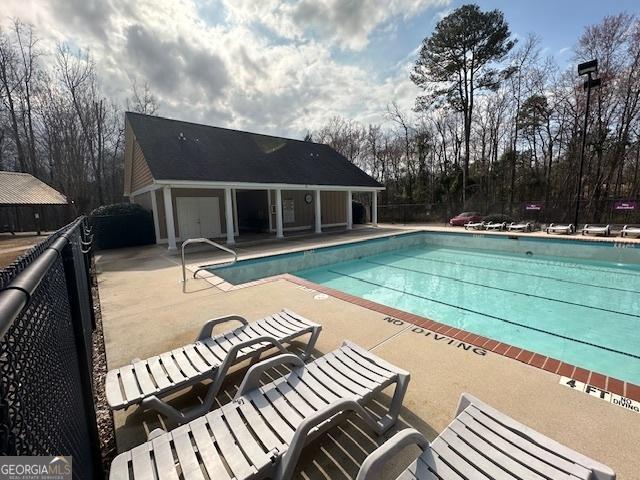 community pool with a patio area and fence