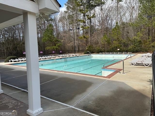 community pool with a patio area and fence