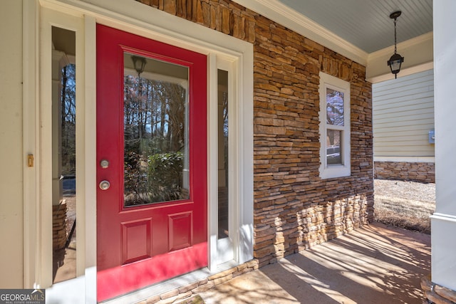 view of exterior entry with a porch and brick siding