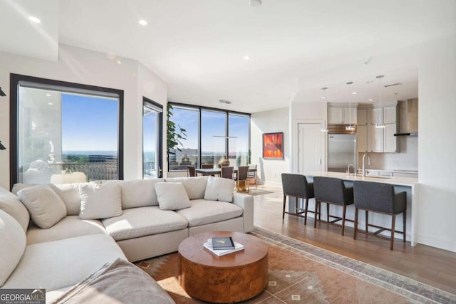 living area with recessed lighting, a healthy amount of sunlight, baseboards, and wood finished floors