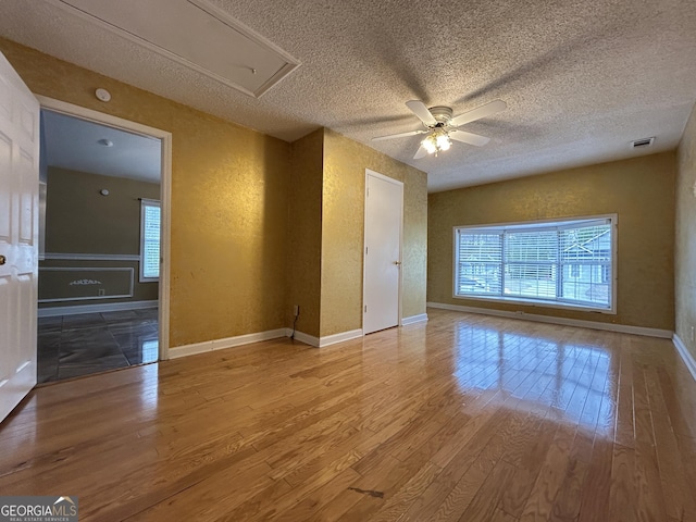 unfurnished room with a textured wall, visible vents, plenty of natural light, and hardwood / wood-style flooring