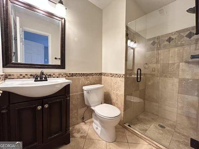 full bath featuring tile walls, toilet, a stall shower, vanity, and tile patterned flooring