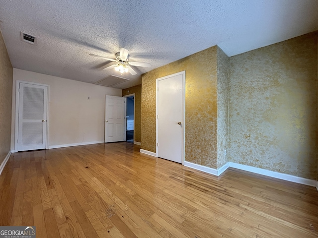 unfurnished bedroom with a textured ceiling, visible vents, hardwood / wood-style flooring, and baseboards