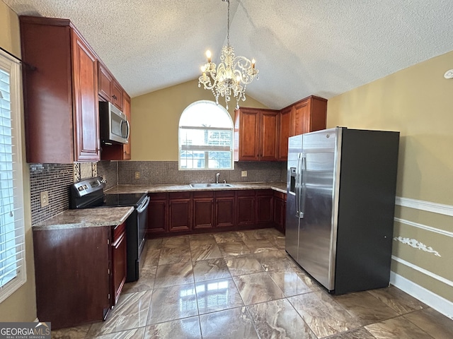 kitchen featuring decorative backsplash, lofted ceiling, appliances with stainless steel finishes, a chandelier, and a sink