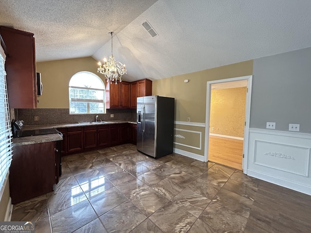 kitchen with lofted ceiling, a sink, visible vents, appliances with stainless steel finishes, and wainscoting