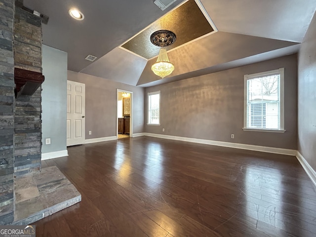 unfurnished living room featuring vaulted ceiling, visible vents, hardwood / wood-style flooring, and baseboards