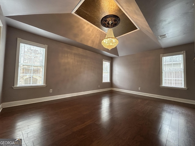 empty room featuring lofted ceiling, baseboards, visible vents, and dark wood finished floors