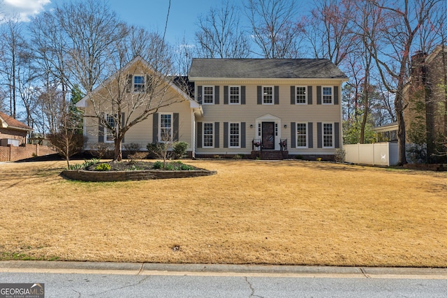 colonial-style house featuring fence and a front yard